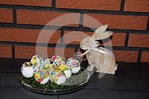 Closer view on easter eggs and a easter bunny in front of a brick wall