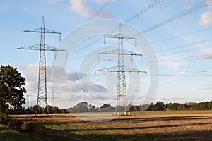 Closer view on electricity pylons under a blue sky and white clouds on a mowed field in geeste emsland germany