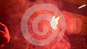 Closer view of a red color sparkling fire crackers releasing smoke while burning