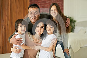 Closest people. Portrait of cheerful latin family, teenage girl and little twin boys smiling at camera while posing with