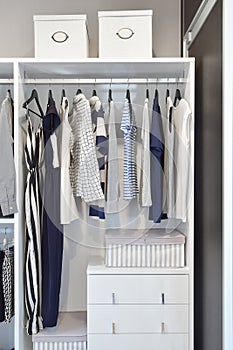 Closet with row of cloths hanging in white wardrobe