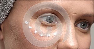 Closeup of 30`s woman`s eue with a eye cream massage it and rub it