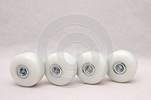 Closeup of 4 white skate wheels against a white background