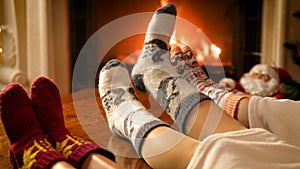 Closeup 4k footage of family feet lying on sofa under blanket warming at burning fireplace