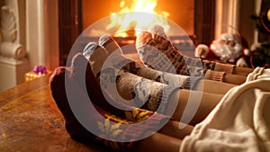 Closeup 4k footage of family feet in woolen socks warming by the burning fireplace