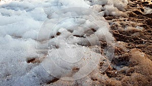 Closeup 4k footage of foam flying aroun on the sandy beach