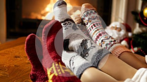 Closeup 4k footage of young family feet in woolen socks lying by the burning fireplace at night
