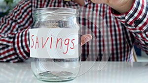 Closeup 4k footage of young man throwing few metal coins in empty money box with savings