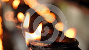 Closeup 4k video of long row of burning oil lamps with sacred fire at hindu temple