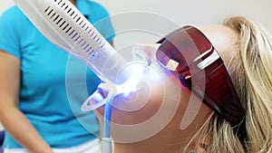 Closeup 4k video of young blonde woman wearing protective UV glasses sitting in dentist chair