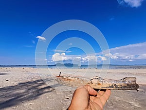 Closeup with an abandoned wooden handmade toy boat on the seaside.