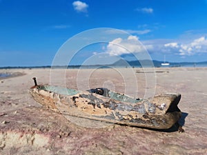 Closeup with an abandoned wooden handmade toy boat on the seaside.