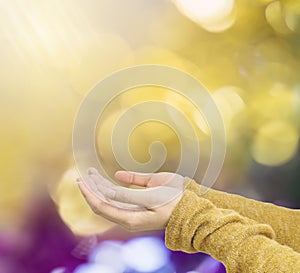 Closeup action of woman hold out hand to wait for good things on abstract blurred colorful light spot bokeh textured background