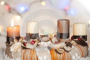 Closeup of Advent wreath with one burning candle and white background with Christmas lights