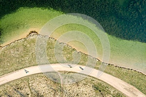 Closeup aerial top view of lake shore with bicycle lane at sunny day