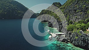 Closeup aerial view of boat at ocean cliff coast with green tropical forest. Exotic nature landscape