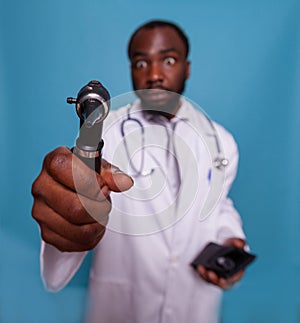 Closeup of african american doctor holding otoscope and acting goofy