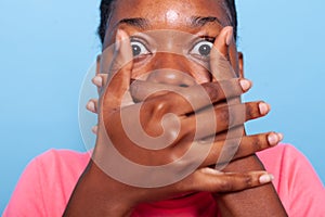 Closeup of african american young woman covering mouth having shocked facial expressions