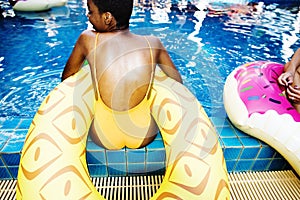 Closeup of african descent woman sitting by the pool with inflatable tubes