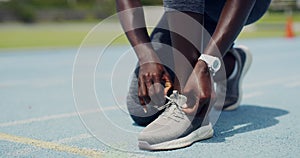 Closeup of an African female athlete tying shoe laces before jogging. Active fit woman ready and preparing to run on a