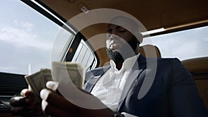 Closeup african man counting money at car. Businessman sitting with money at car