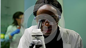 Closeup of african researcher woman looking at leaf slide under microscope