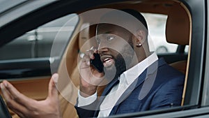 Closeup afro man talking phone at car. Man sitting at front seat at luxury car