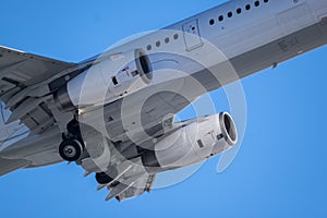 Closeup of an airplane fuselage, wings and jet engines against the bright blue sky