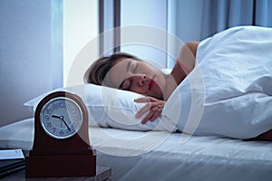 Closeup alarm clock having a good night with background happy woman sleeping in bed