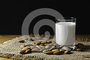 Closeup almonds and glass milk on wooden background with copy space