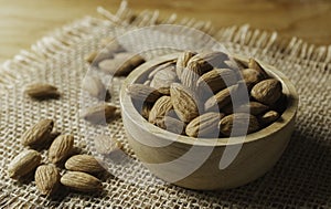 Closeup almonds in wooden bowl on sackcloth almond concept with copy space