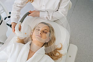 Closeup of anti acne phototherapy with professional equipment. Beautiful woman with closed eyes during photo