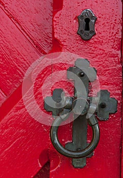 Closeup of an antique door handle and keyhole on a wooden red do