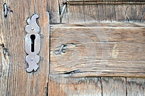 Closeup of antique wooden door with metallic keyhole and nails