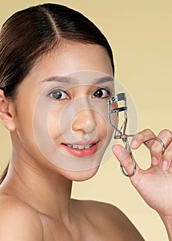 Closeup ardent woman model with flawless beautiful skin using eyelash curler.