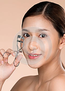 Closeup ardent woman model with flawless beautiful skin using eyelash curler.