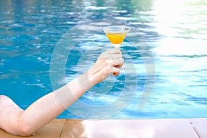 closeup arm of woman drinking beverage in poolside, happy life on summer