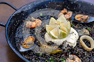 Closeup of Arros negre served on a pan in a restaurant photo