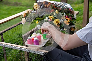 Closeup of an artist& x27;s hands painting silk flowers outdoors