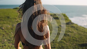 Closeup Asia beach bokeh: woman look on water wave in summer sun day. Girl on high green grass cliff