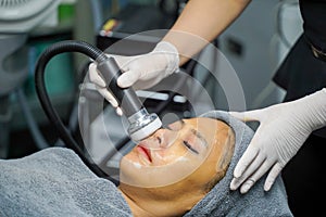 Closeup Asian beauty woman having therapy to stimulate facial skin and facial ultrasonic skincare treatment by professional