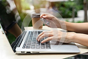 Closeup of Asian businesswoman typing on computer while holding credit card, Female shopping online or booking ticket. New normal