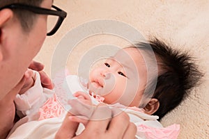 Closeup asian father sing or talk with adorable daughter on bed, close up dad eye contact with healthy newborn 3 months with love