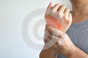 Closeup of asian male arms holding his painful wrist caused working hard on the computer, laptop. Office syndrome hand pain by