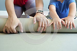 Closeup Asian mother and little son hands rolling exercise mat