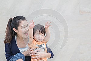 Closeup asian mother and son in happy motion on marble stone wall textured background with copy space