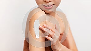 Closeup of Asian woman applying body cream on shoulder