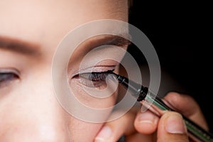 Closeup asian woman applying eyeliner on eye