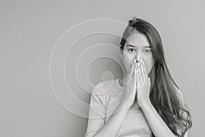 Closeup asian woman in shocking motion with something blurred cement wall textured background in black and white tone with copy sp