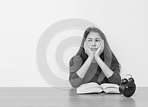 Closeup asian woman sitting for read a book with bored emotion and thinking face on wood table and white cement wall textured back